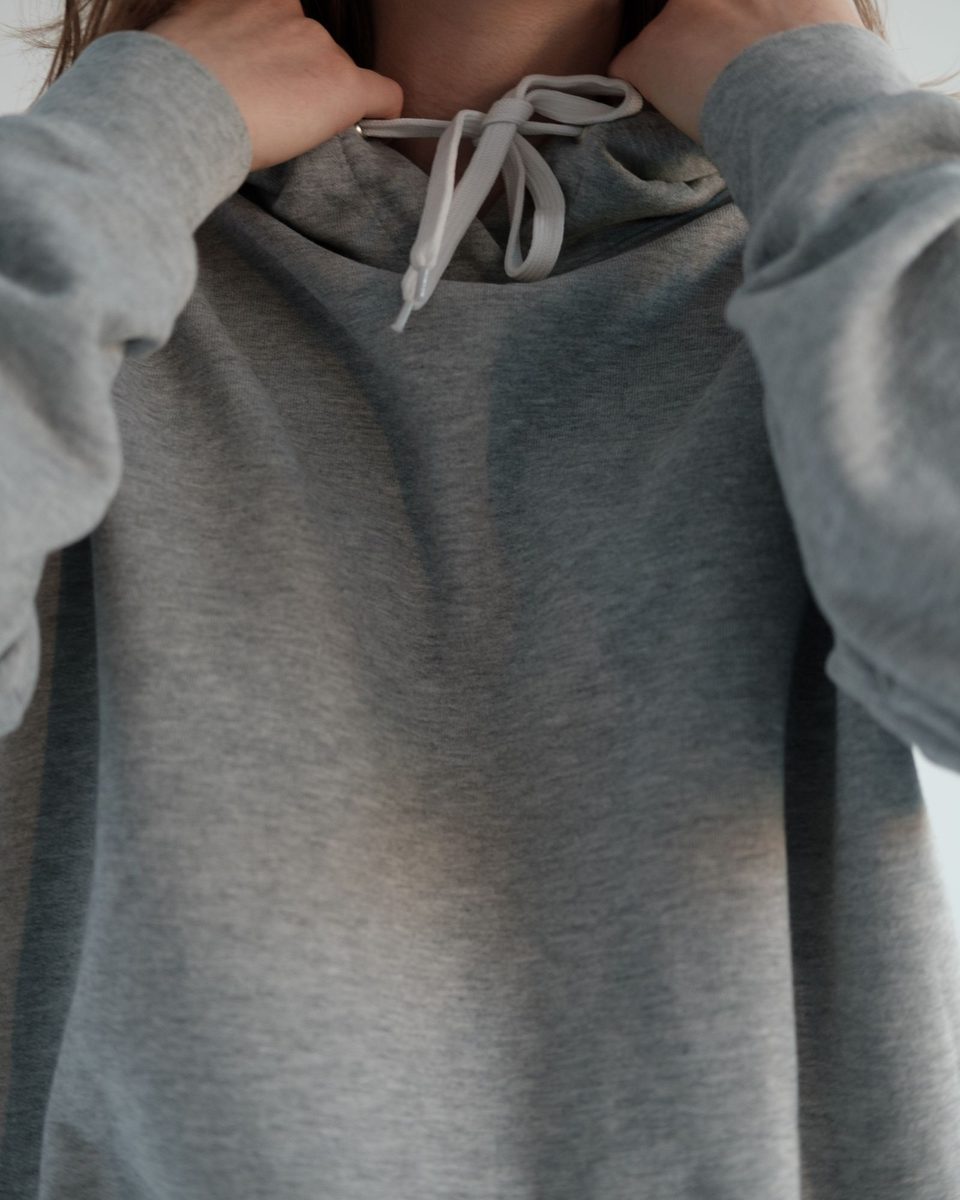 The neck and drawcords of a grey marl hoodie, close up